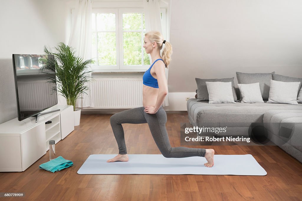 Young woman exercising on exercise mat in living room, Bavaria, Germany