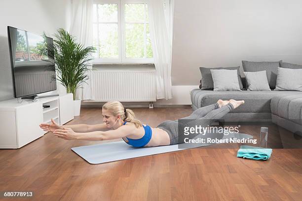 young woman exercising on exercise mat in living room, bavaria, germany - de bruços imagens e fotografias de stock