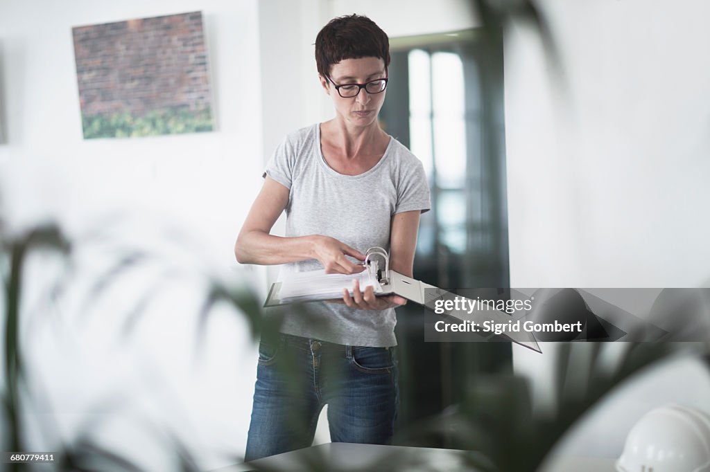 Mature woman looking at paper in the office, Freiburg im Breisgau, Baden-Württemberg, Germany