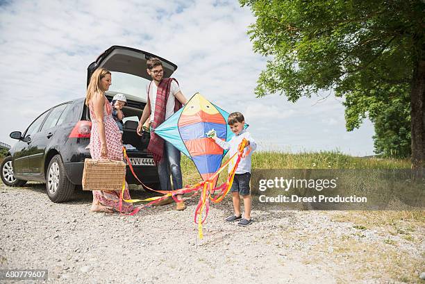 family with kite unloading the car on meadow in the countryside, bavaria, germany - kite toy stock-fotos und bilder
