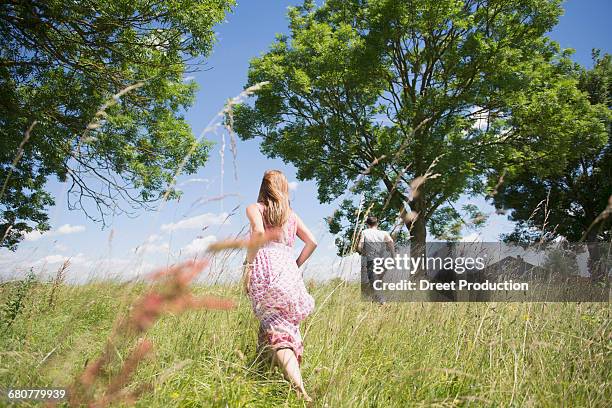 rear view of mid adult couple running through grass on meadow in the countryside, bavaria, germany - tall high stock-fotos und bilder