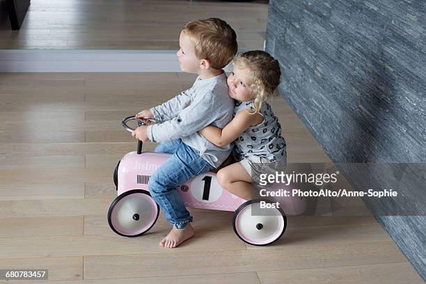 Young siblings riding on toy car together