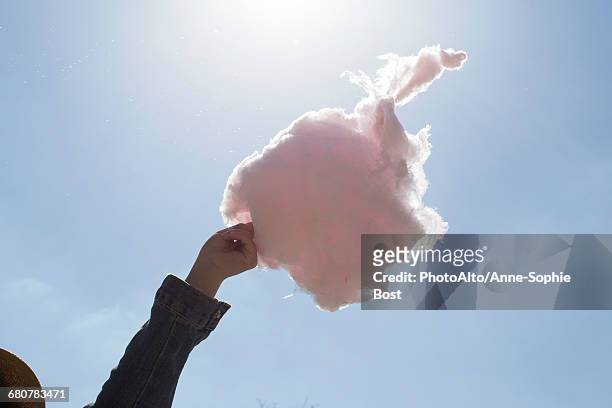 hand holding cotton candy against blue sky - cotton candy stock-fotos und bilder
