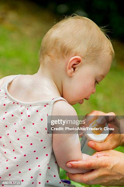 parent spraying sunscreen on babys arm - baby suncream stock pictures, royalty-free photos & images