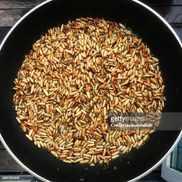 toasted pine nuts in a frying pan - pine nut stock pictures, royalty-free photos & images