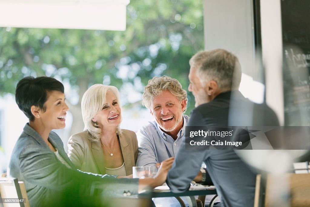 Smiling couples talking and dining at restaurant table