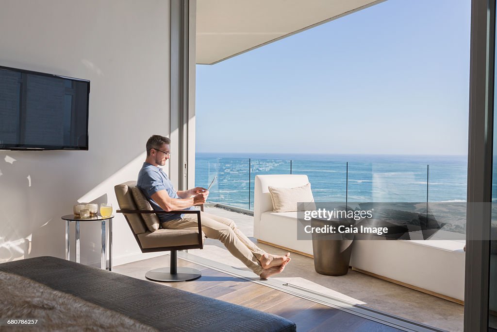 Man using digital tablet overlooking sunny ocean view