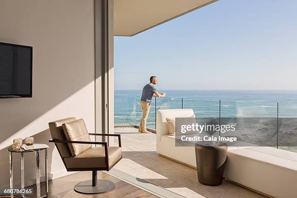 man enjoying sunny ocean view from luxury balcony - beach house balcony fotografías e imágenes de stock