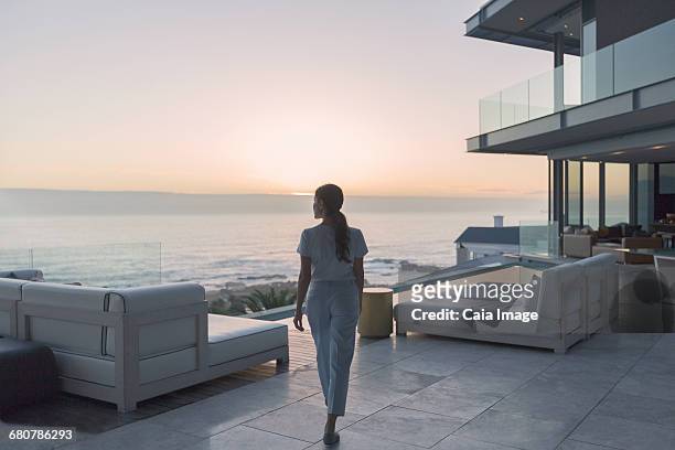 woman walking on luxury home showcase exterior patio at sunset - beach house balcony stock pictures, royalty-free photos & images