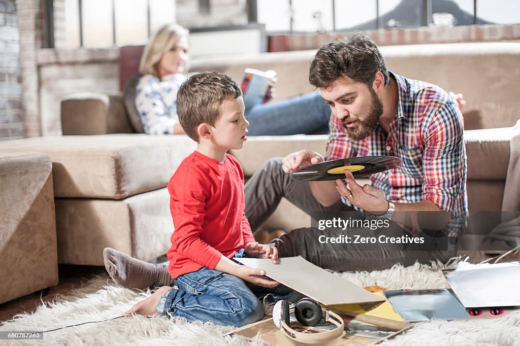 Father showing vinyl record to son at home