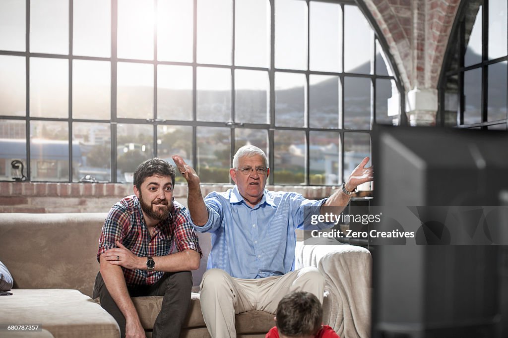 Father and son watching television at home