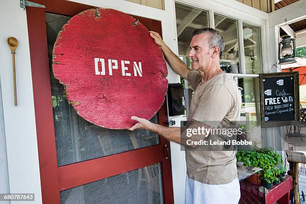 cafe owner putting up signage on front door - open round one stock pictures, royalty-free photos & images