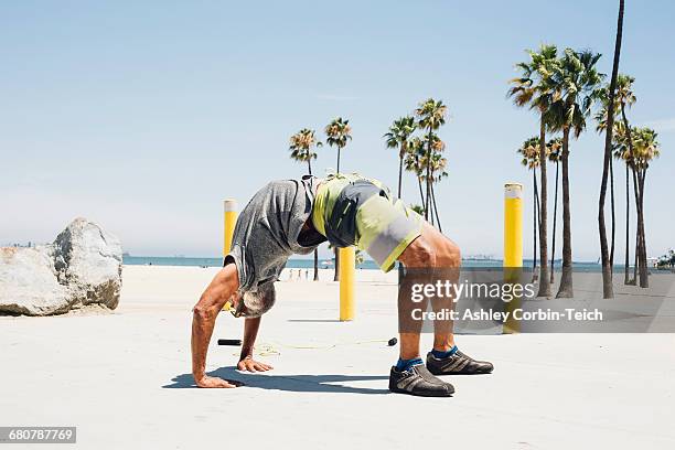 senior man, exercising on beach, in yoga position, long beach, california, usa - bending over backwards stock pictures, royalty-free photos & images