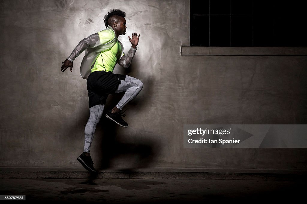 Young man with mohawk, exercising at night, in urban setting