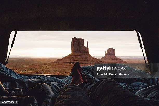 male legs and feet relaxing inside four wheel drive with view of sandstone buttes from car boot, monument valley, arizona, usa - male feet imagens e fotografias de stock
