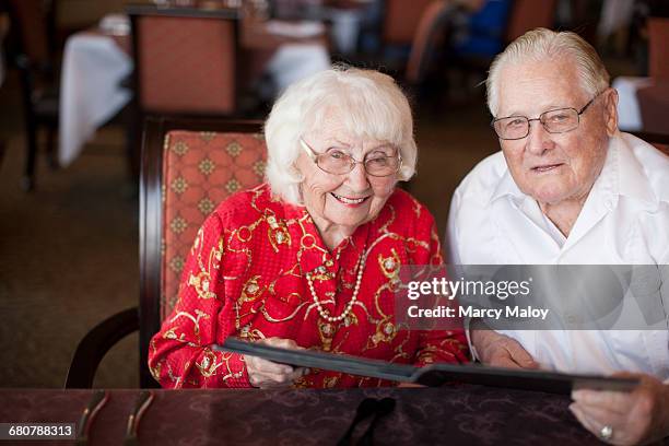 portrait of senior couple sitting at table in restaurant, smiling - mais de 90 anos - fotografias e filmes do acervo