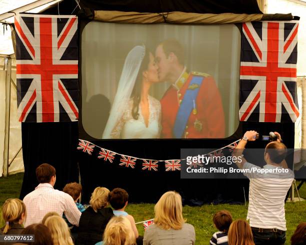 People watch as a big screen in a tent shows the first kiss at a gathering in Bucklebury near Reading on the day that Kate Middleton married Britains...
