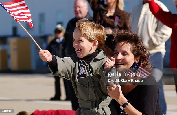 Six-year-old Matthew Mitchell and his mother Dana Mitchell wave American flags as the F14 Tomcat flown by her husband Lt. Eric Mitchell taxis to the...