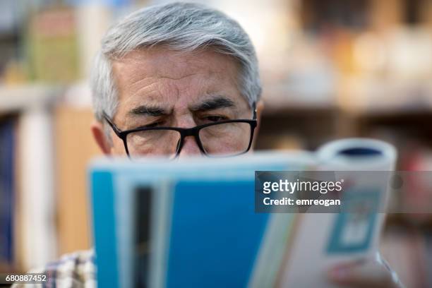 man reading book in bookstore - emreogan stock pictures, royalty-free photos & images