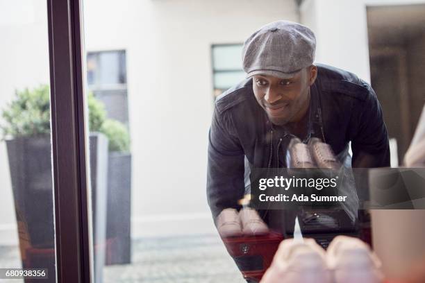 man in leatherjacket window shopping at a shoe store - alternative view stock-fotos und bilder