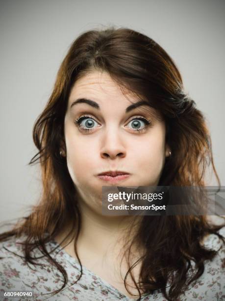 mujer joven disgustada soplando mejillas - mejilla fotografías e imágenes de stock