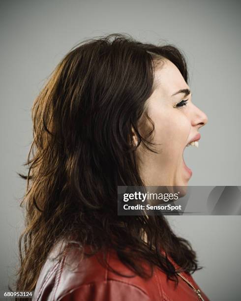 young woman screaming against gray background - annoyed face brunnette stock pictures, royalty-free photos & images