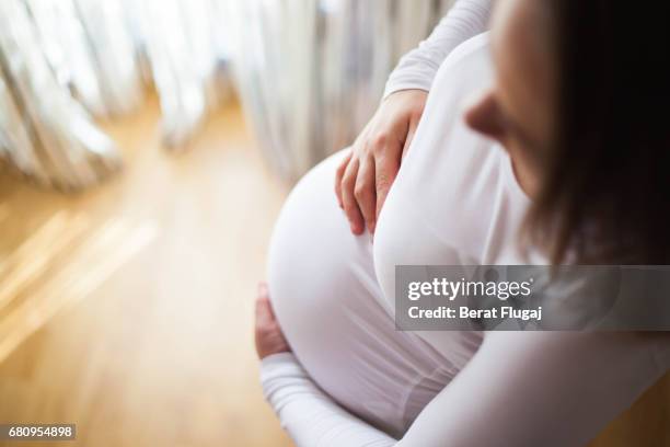 a pregnant lady holds bump thoughtfully - human abdomen ストックフォトと画像