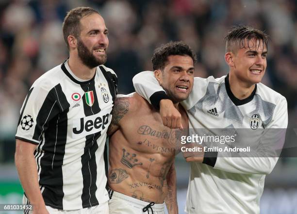 Paulo Dybala of Juventus FC celebrates with his team mates Daniel Alves da Silva and Gonzalo Higuain the victory at the end of the UEFA Champions...