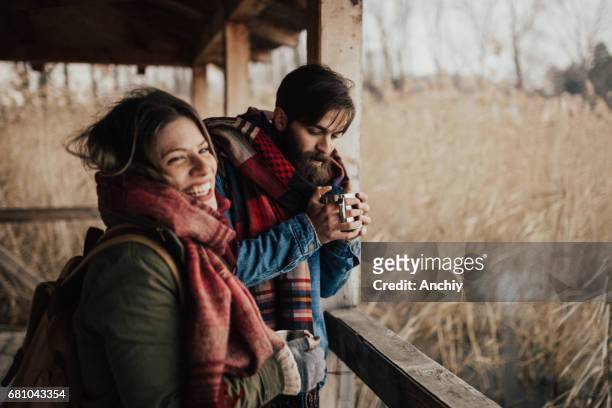 happy couple drinking hot tea on a cold day - couple camping stock pictures, royalty-free photos & images