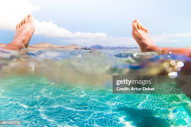 guy resting on water from personal perspective in the stunning lagoon beach with turquoise and crystal waters in the south of fuerteventura island during travel vacations in the island. - wonderlust imagens e fotografias de stock