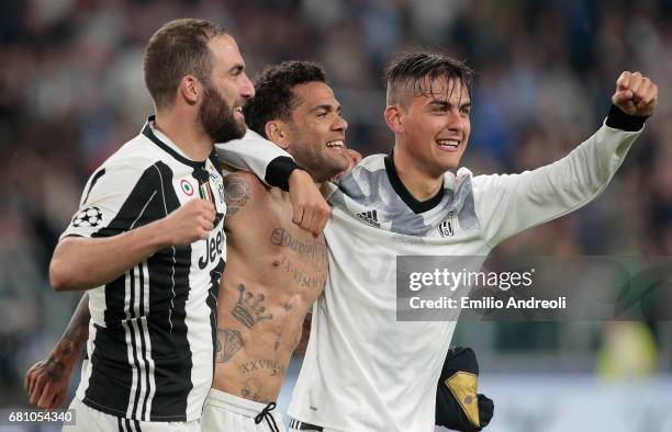 Paulo Dybala of Juventus FC celebrates with his team mates Daniel Alves da Silva and Gonzalo Higuain the victory at the end of the UEFA Champions...