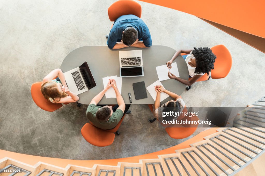 View from above towards five business people around meeting table