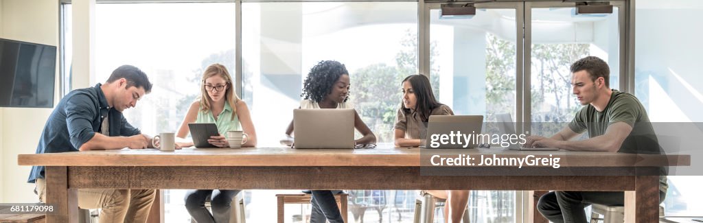 Profesionales creativos trabajando en computadoras portátiles en espacio de coworking