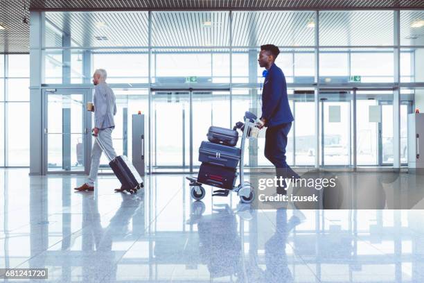 pasajeros con equipaje en la terminal del aeropuerto - carrito-para-equipaje fotografías e imágenes de stock
