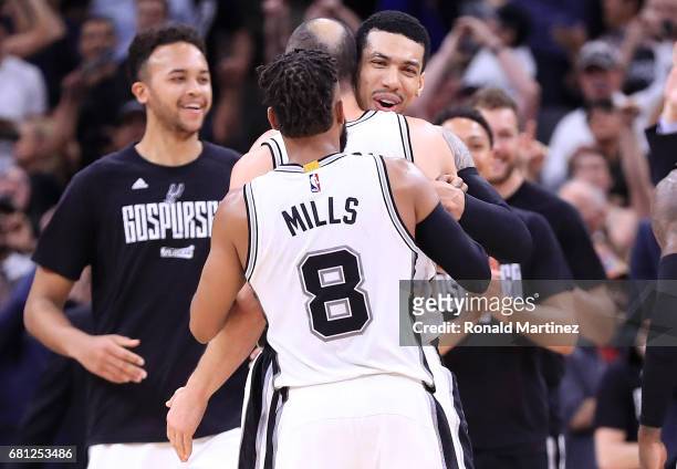 Danny Green hugs Manu Ginobili and Patty Mills of the San Antonio Spurs after an overtime win against the Houston Rockets during Game Five of the...