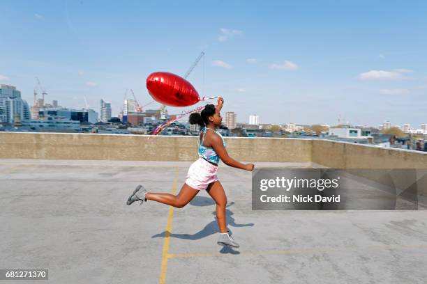 young teenage girl running on rooftop overlooking the city - balloon girl fotografías e imágenes de stock