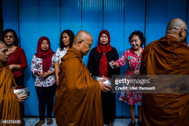 Buddhist monks receive religious alms from Buddhist followers as they walk around the streets during Pindapata procession on May 10, 2017 in...