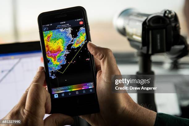 Support scientist Tim Marshall, a 40 year veteran of storm chasing, monitors radar on his smartphone as they wait for thunderstorms to develop during...