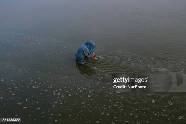 An indian hindu woman devotee performs prayers in Polluted banks of Ganges River, in Allahabad on May 9,2017.