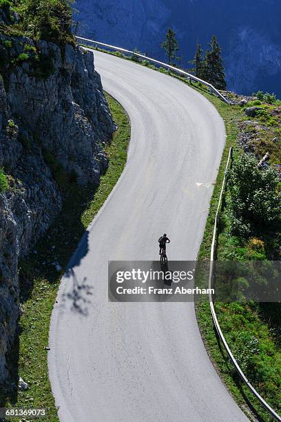 lonesome cyclist on mountain road - mountain road cliff stock pictures, royalty-free photos & images