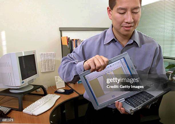 Charlton Lui , a Microsoft development manager, rotates the screen of an Acer tablet PC prototype after undocking it November 7, 2001 from a...