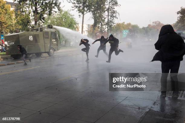 Demonstrator is detained under water launched by water cannons by riot police, in Santiago, Chile, on May 9, 2017. Under the banner: &quot;End to...