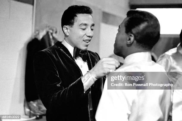 Smokey Robinson helping tie a tie for Warren 'Pete' Moore of the Miracles in a boys locker room before going onstage at Evanston High School in...