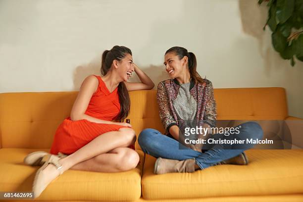 two diverse women talk on couch - yellow dress stock-fotos und bilder