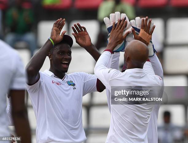 Jason Holder of the West Indies celebrates with bowler Roston Chase after taking the catch of Shan Masood of Pakistan on the first day of play,...