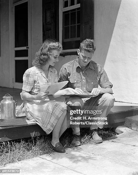 1940s YOUNG COUPLE MAN WOMAN SITTING ON PORCH OF FARM HOUSE REVIEWING LEDGER PAPERS METAL MILK CONTAINER BY WOMAN