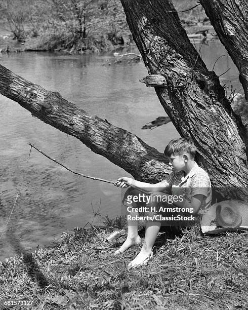 1940s BAREFOOT BOY SITTING UNDER TREE BY STREAM FISHING WITH TWIG POLE