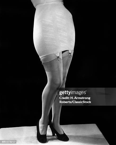 1940s FASHION WOMAN FROM WAIST DOWN WEARING GIRDLE WITH GARTERS CLIPS HOLDING SILK NYLON HOSE STOCKINGS