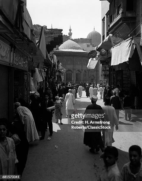 1920s 1930s EGYPTIAN PEOPLE ANONYMOUS SILHOUETTED PEDESTRIANS IN STREET SCENE MOSQUE AT END OF STREET CAIRO EGYPT
