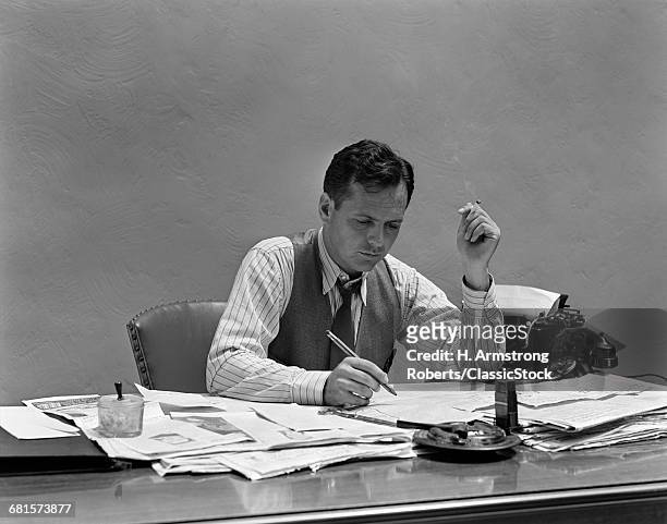 1930s 1940s STRESSED BUSINESSMAN WORKING AT DESK FULL OF PAPERS FILES AND MAIL WEARING SHIRTSLEEVES TIE VEST SMOKING CIGARETTE